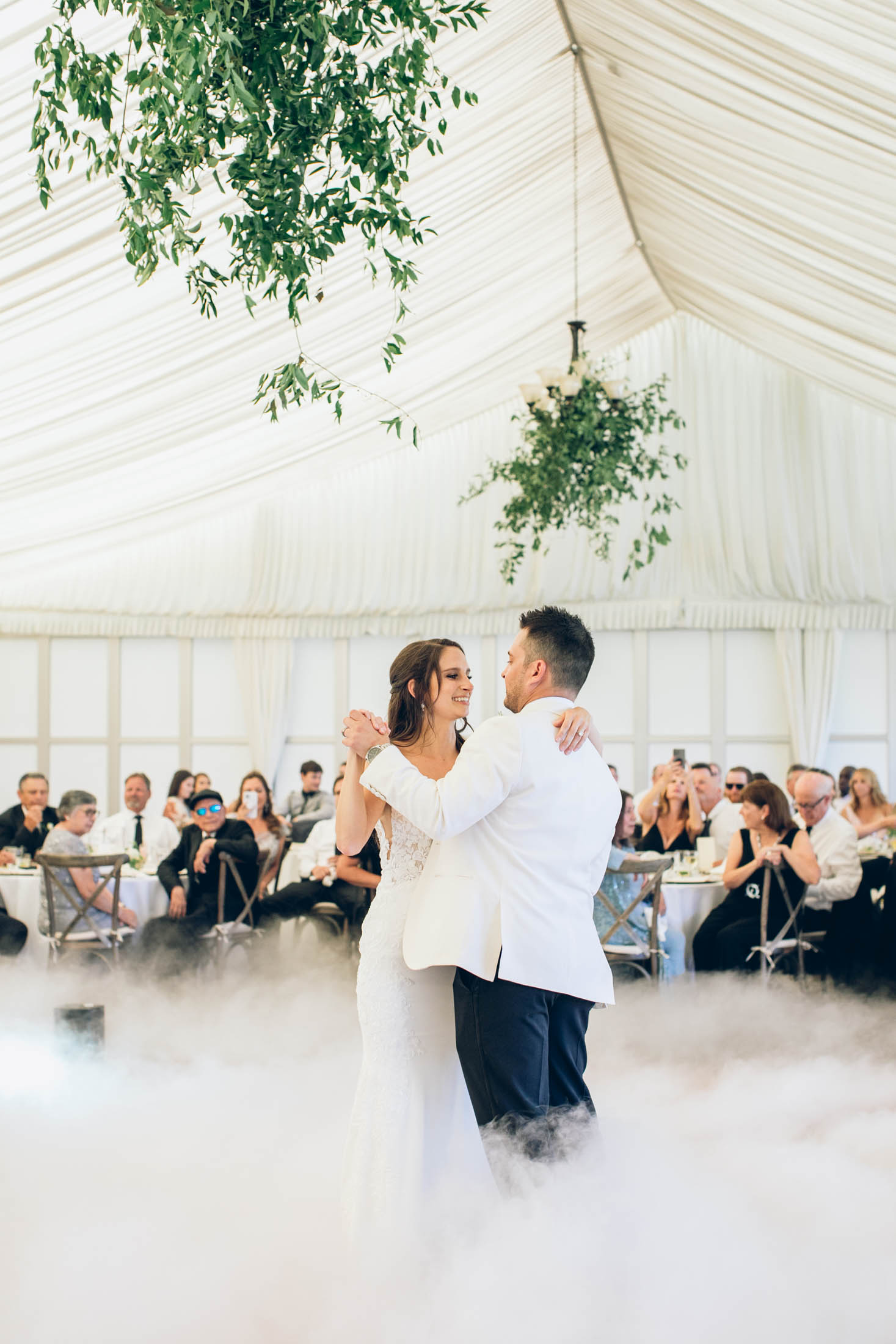 A bride and groom dance in front of a crowd of people.