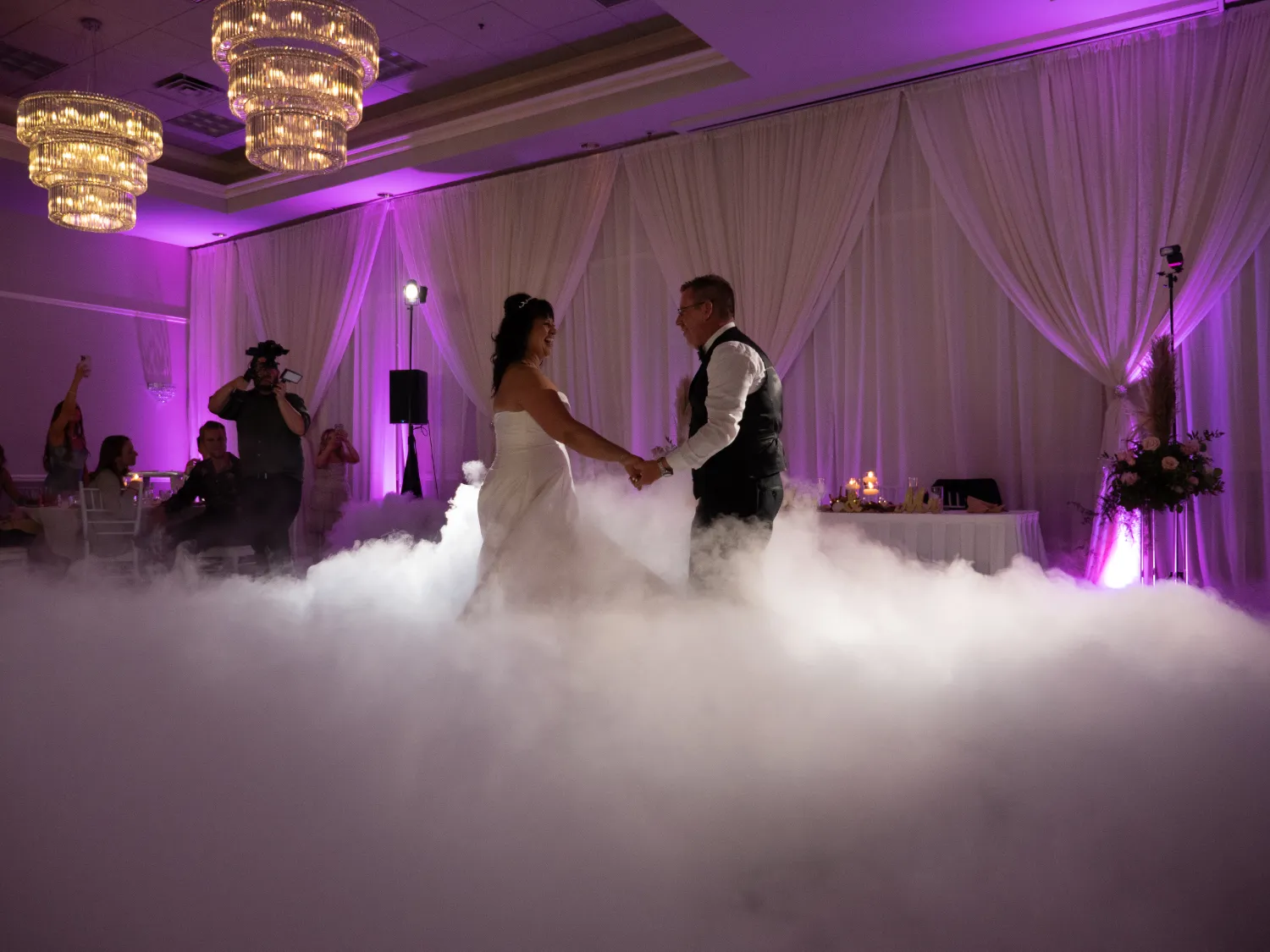 A bride and groom dance in a cloud of smoke.