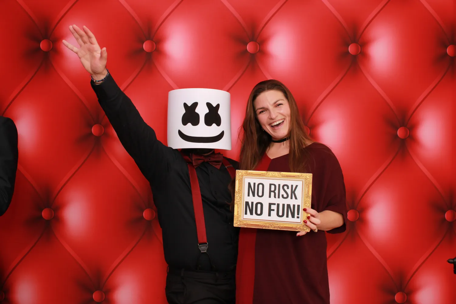 Marshmello and woman pose with "No Risk No Fun" sign on red background