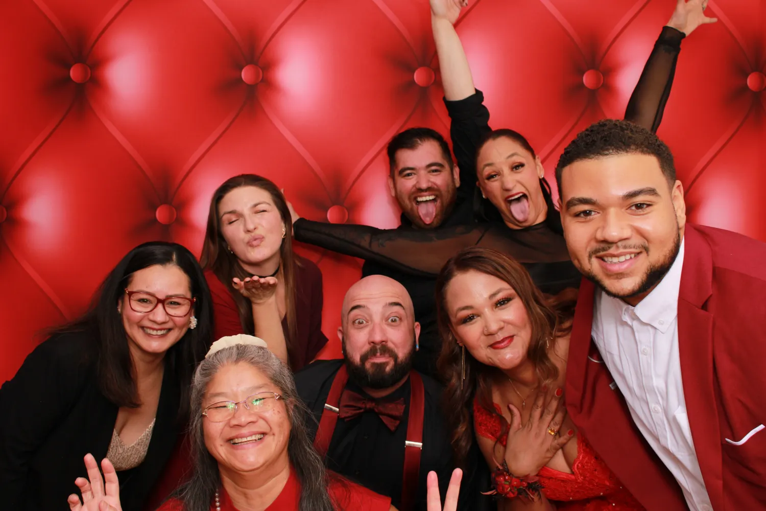 Diverse group of people posing playfully in front of red tufted background