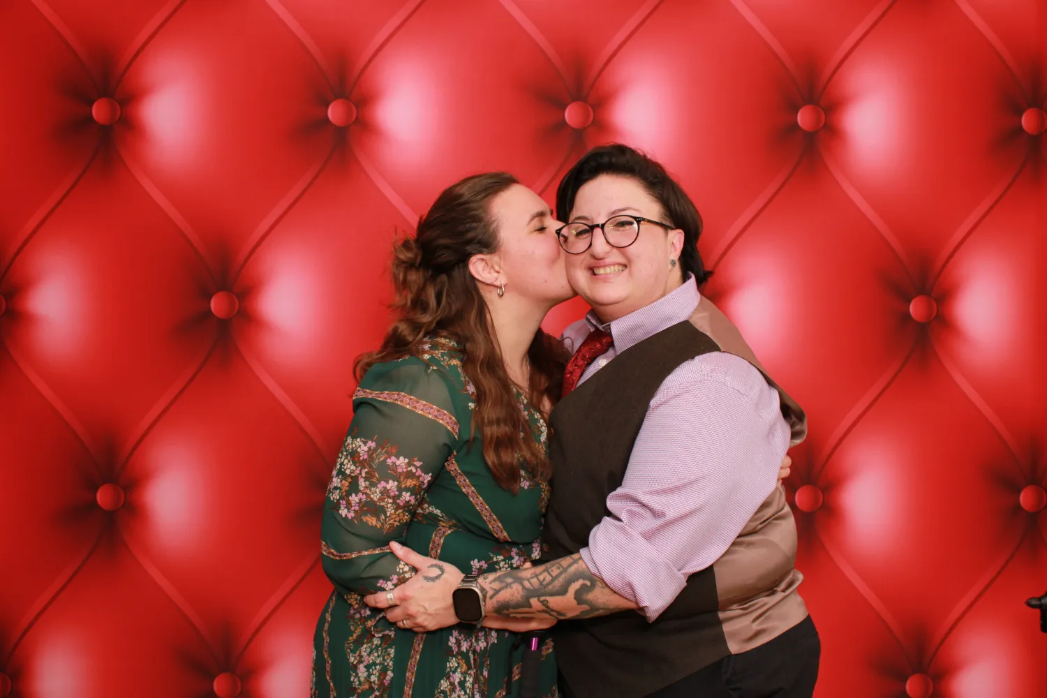 Couple embracing and kissing against a luxurious red tufted backdrop