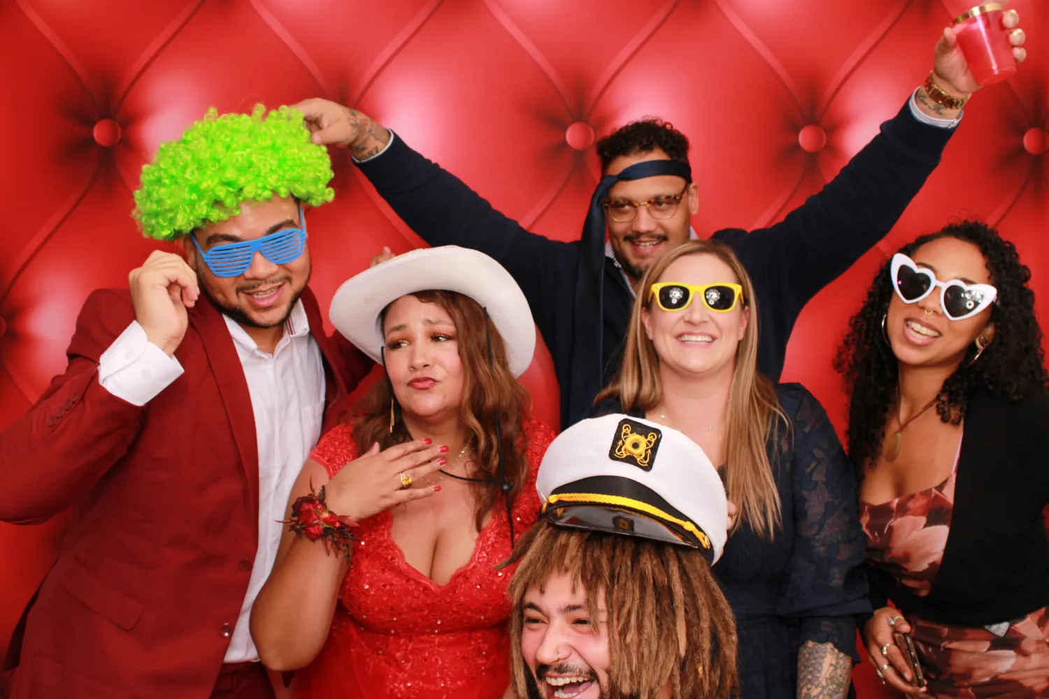 Festive group in photo booth with colorful costumes and funny sunglasses