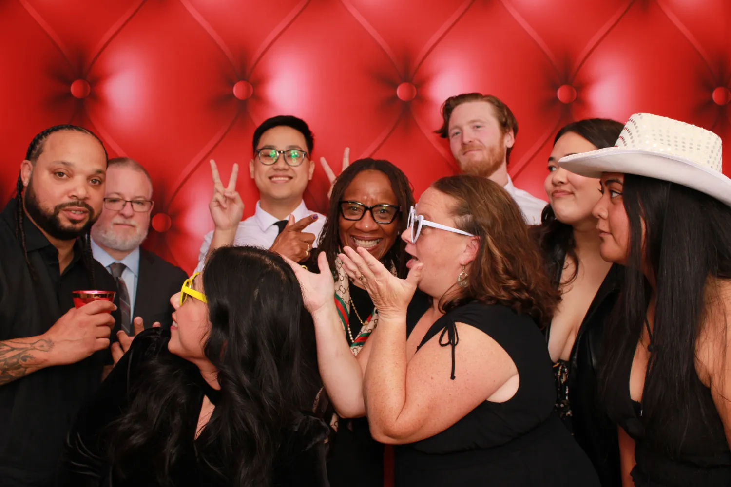 Diverse group of colleagues celebrating together in front of red backdrop