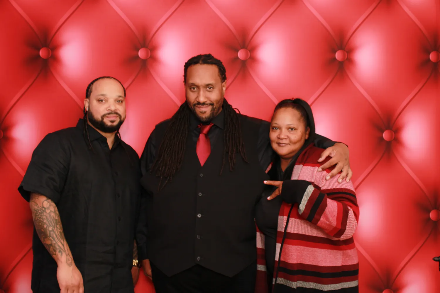 Three people posing in front of a red tufted backdrop