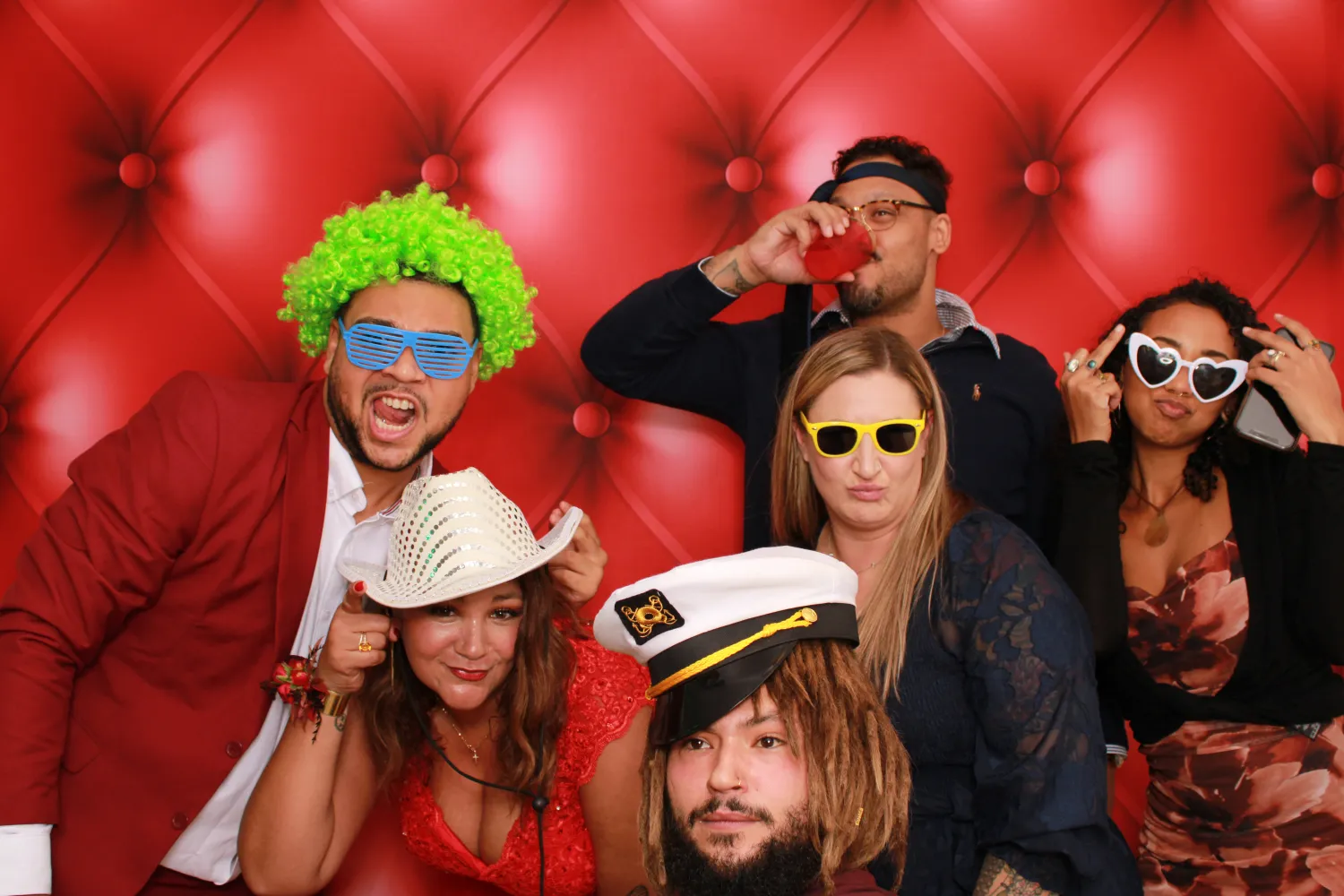 Friends in colorful costumes and sunglasses posing in a photo booth