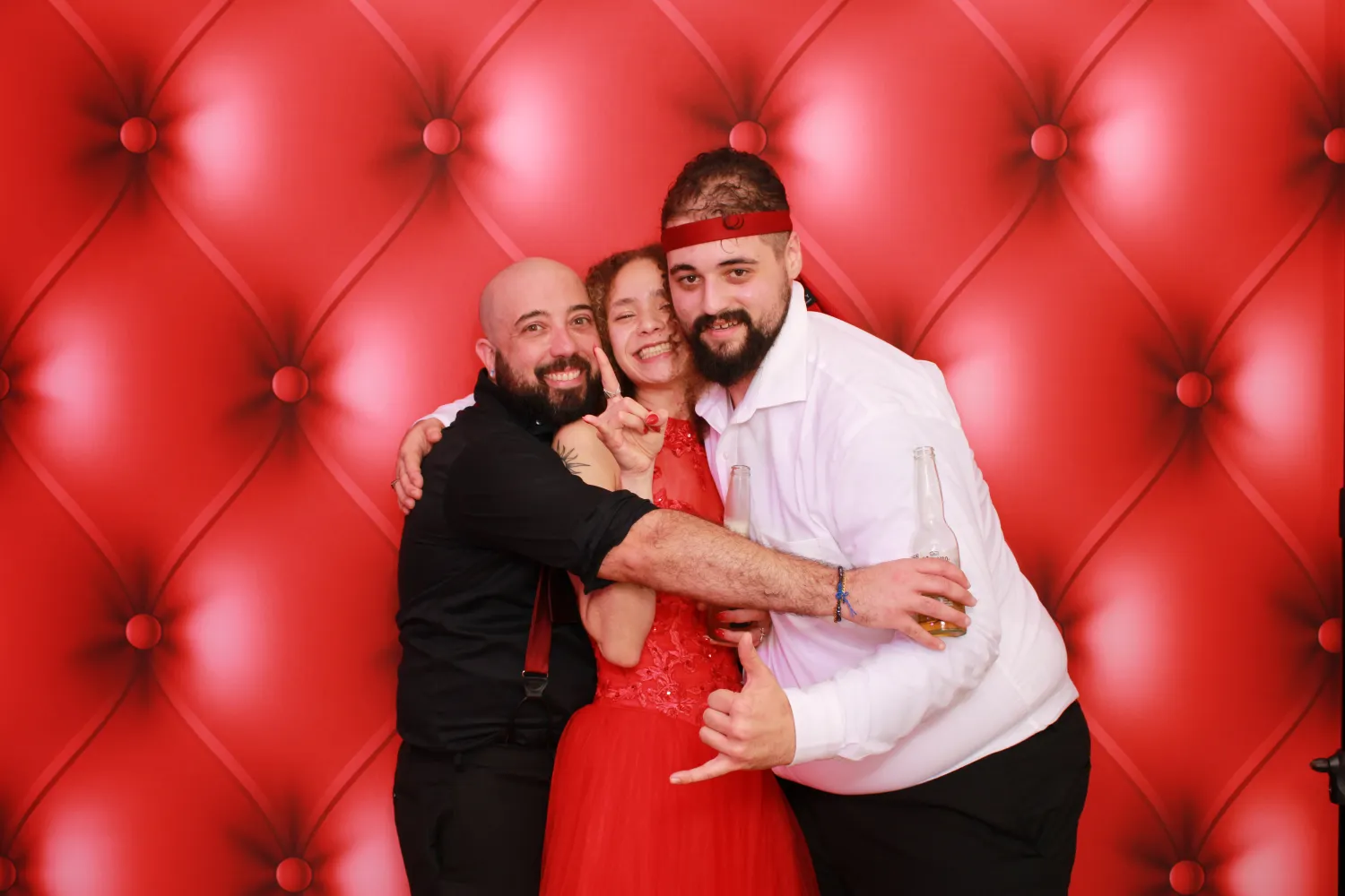 Three friends in festive red backdrop, hugging and smiling together
