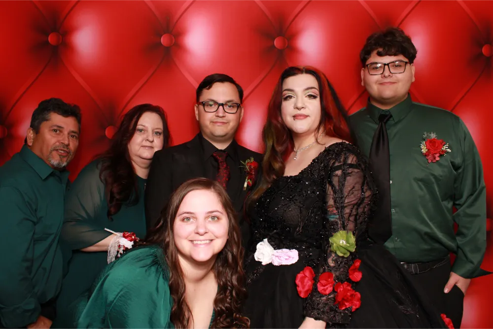 Six people pose together in front of a red tufted background