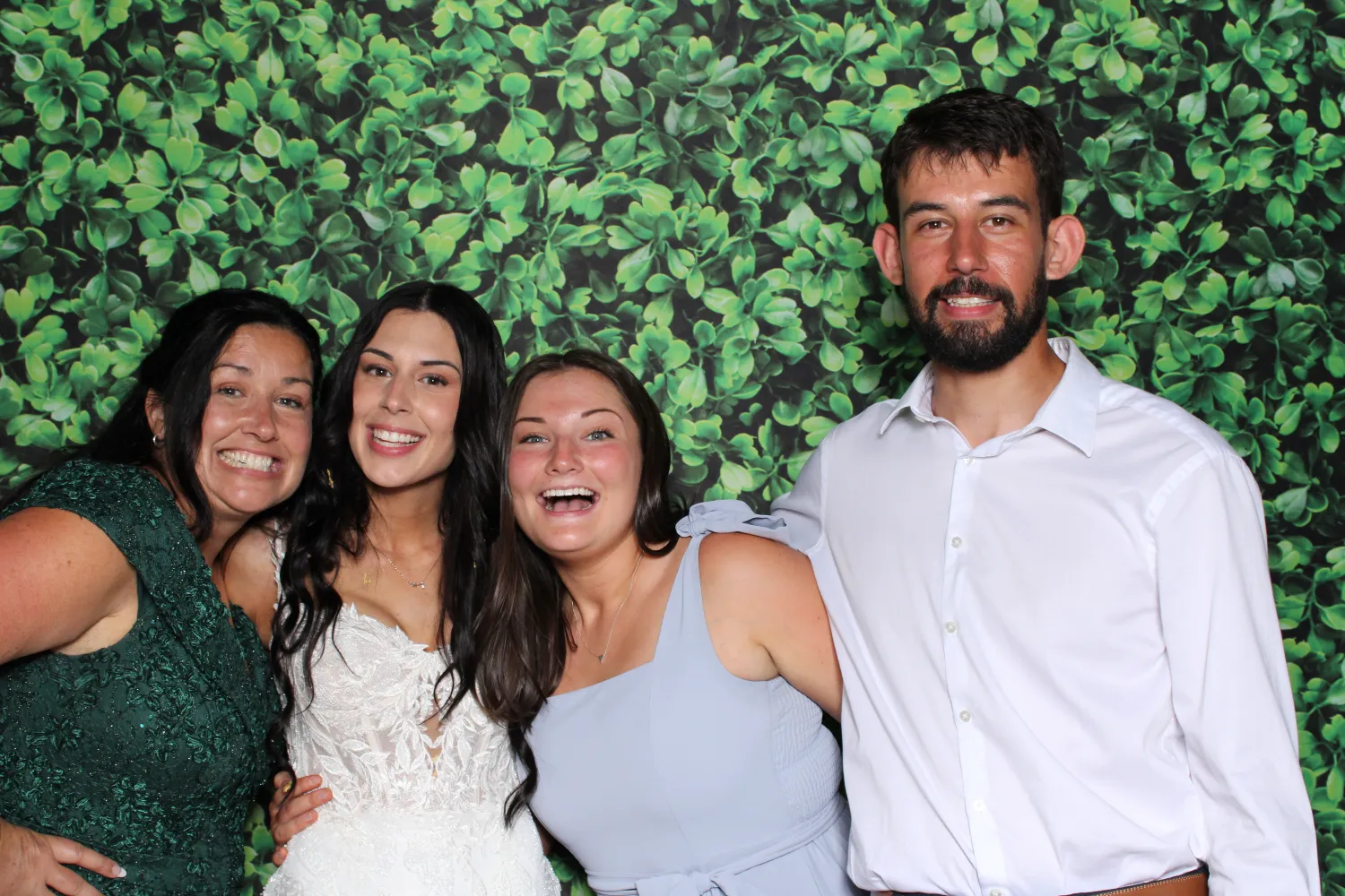 Four people smiling together in front of a green leafy backdrop