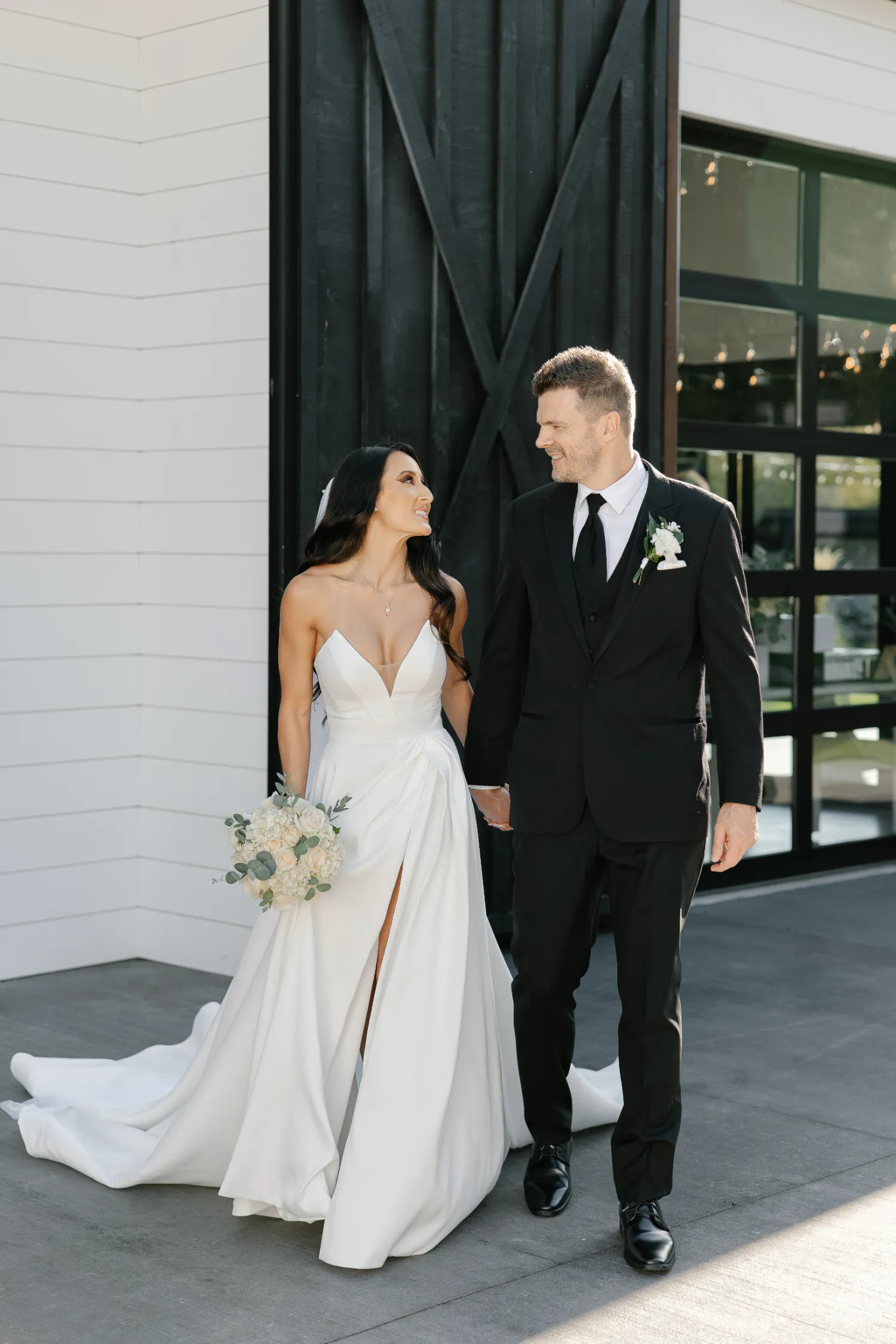 Bride and groom holding hands, smiling in elegant wedding attire