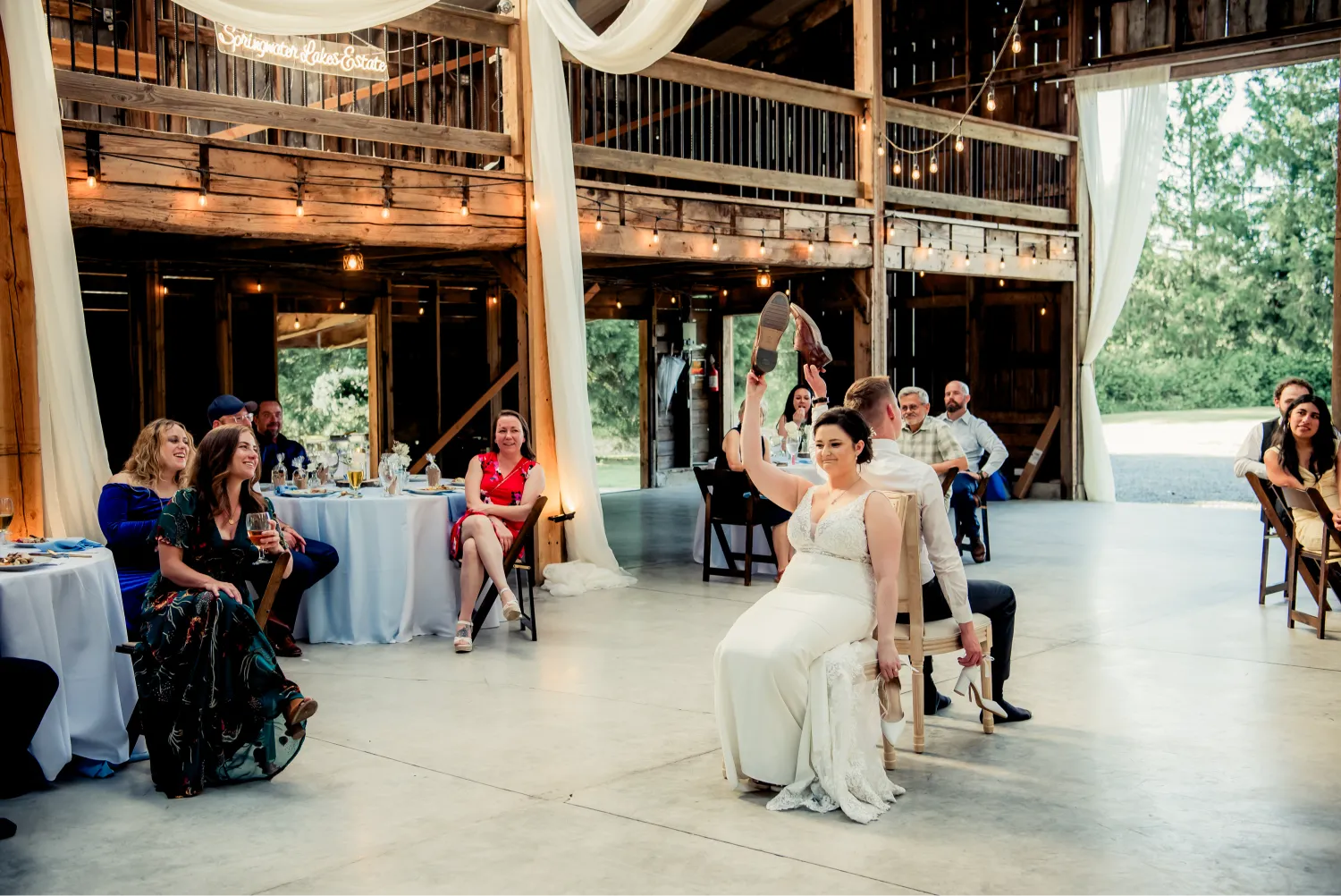 Wedding reception in rustic barn with string lights and guests sitting