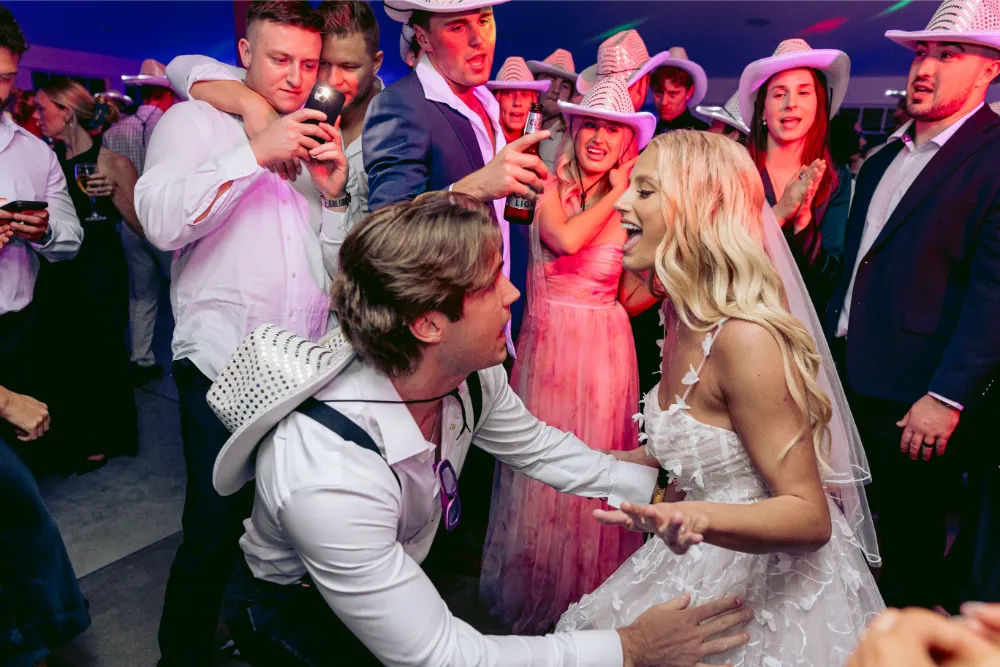 Joyful wedding reception with dancing bride and guests in cowboy hats