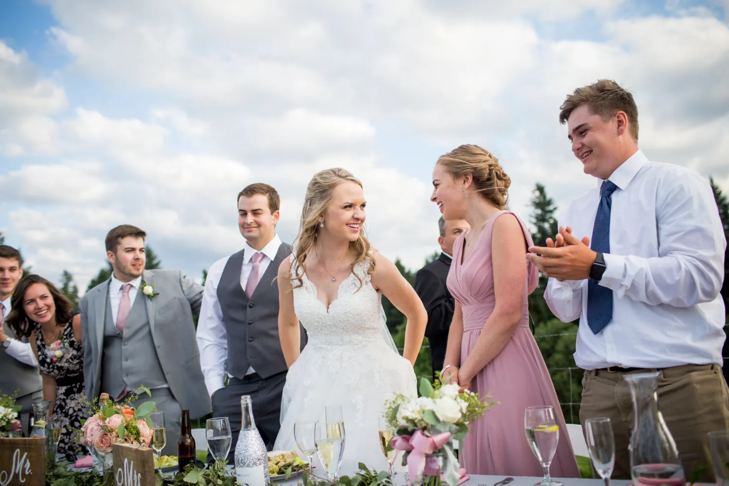 Bride and wedding party celebrating outdoors with floral decor and champagne