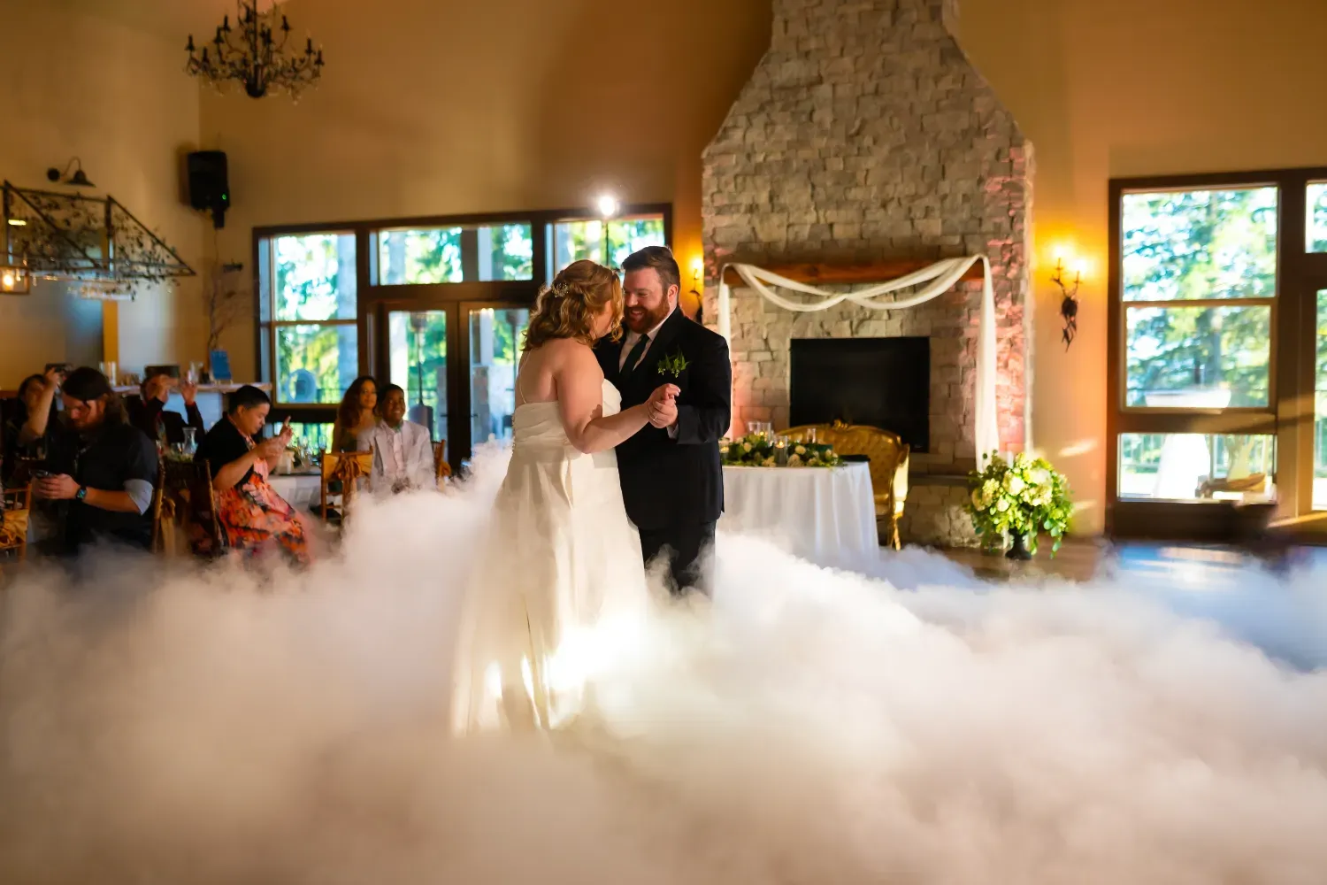 Wedding couple dancing on cloud-like fog in rustic stone venue