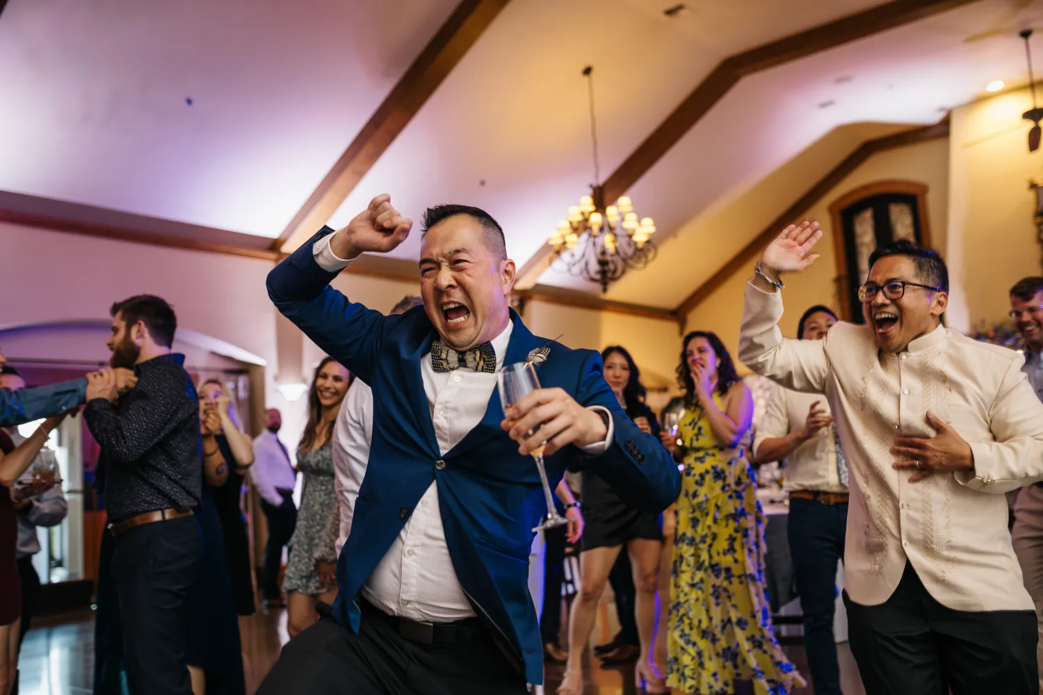 Excited guest in blue suit celebrating and dancing at a wedding reception