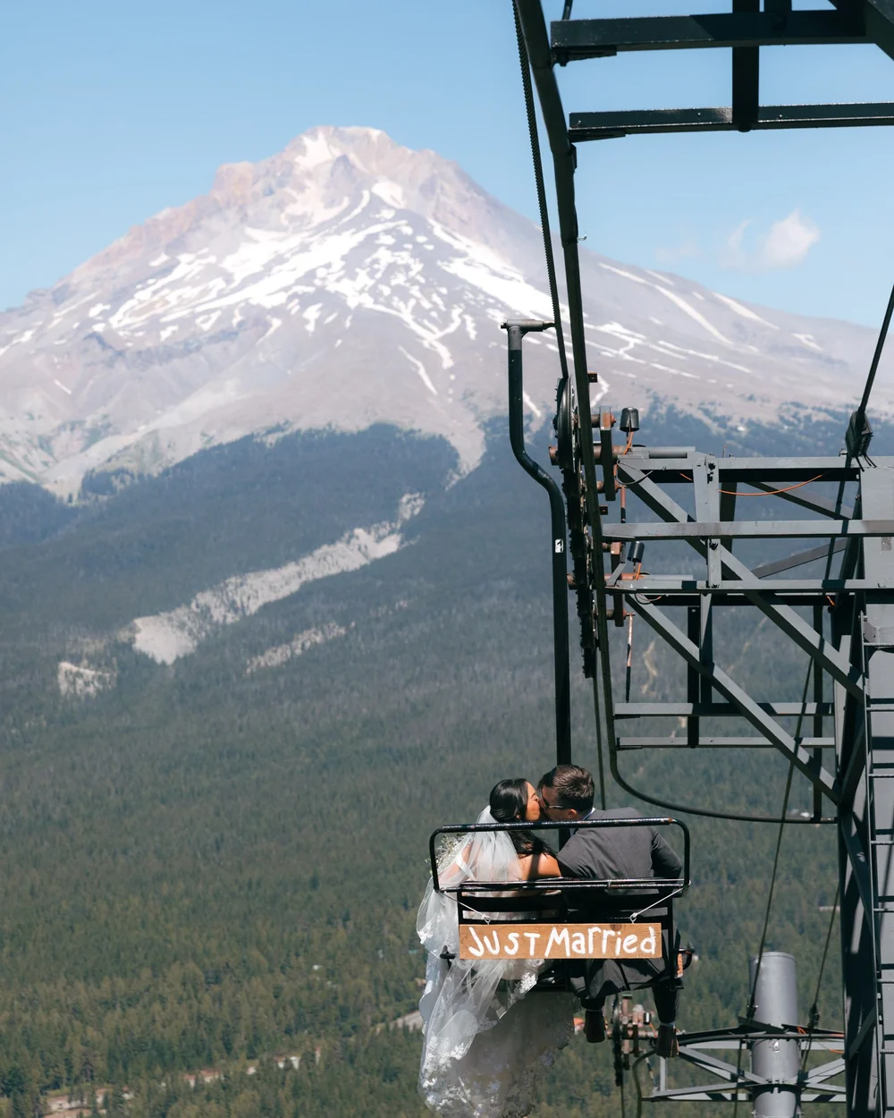 Just married couple on ski lift with snowy mountain backdrop