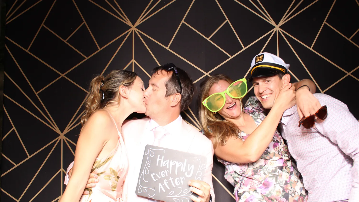 Couples in photobooth celebrate wedding with fun props and kiss