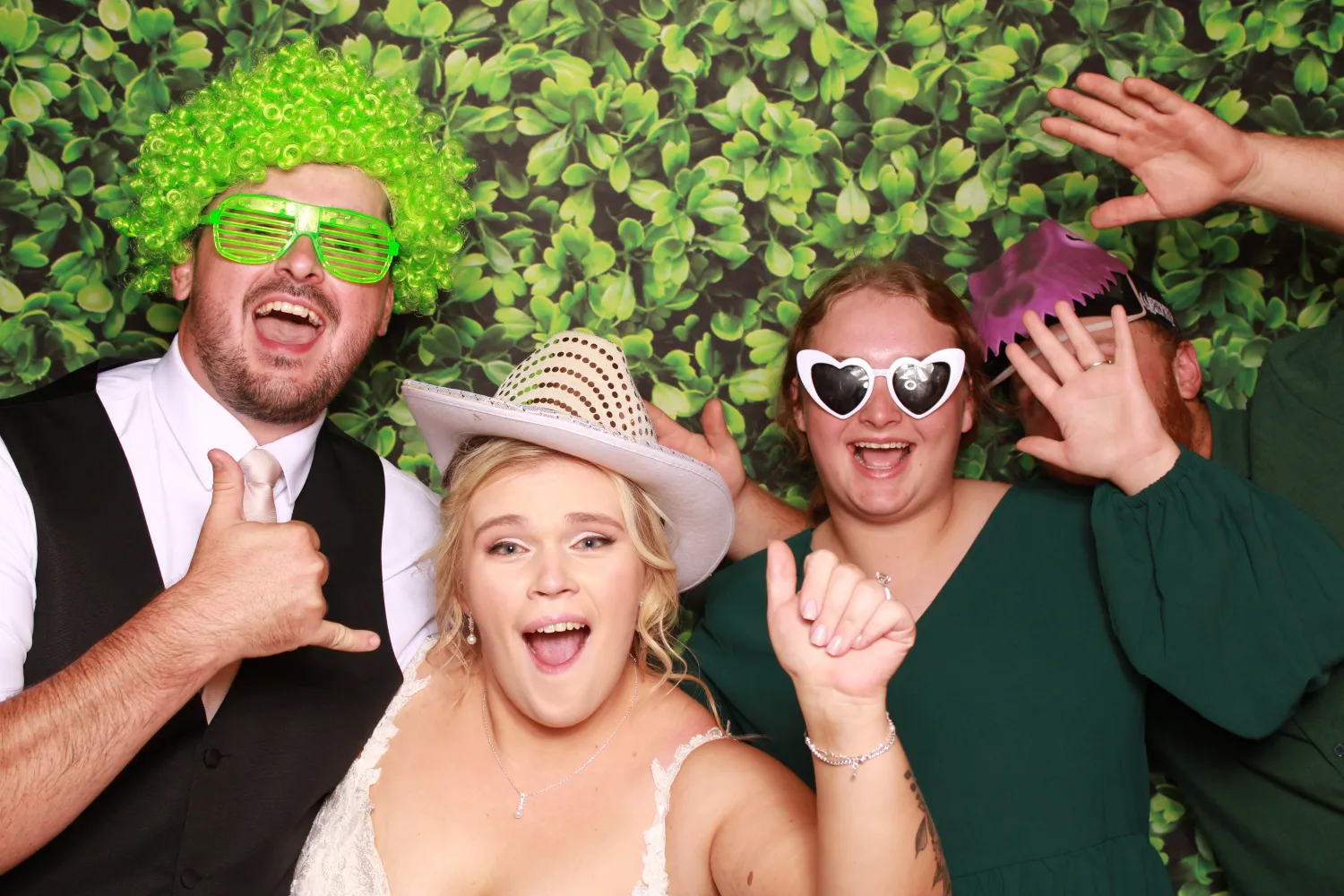 Joyful wedding guests in fun photo booth with crazy props and backdrop