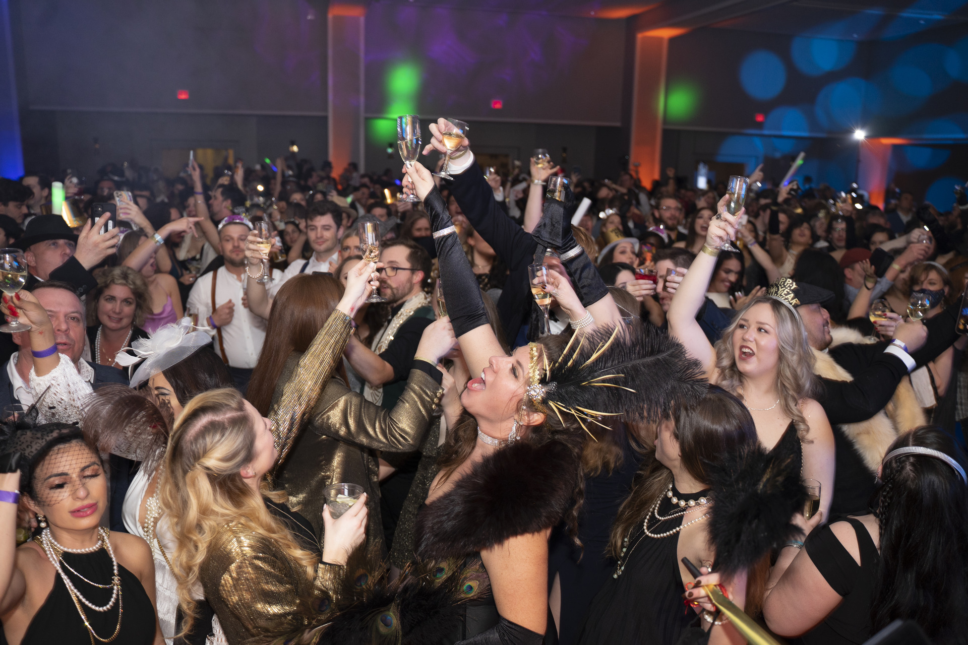 Crowded New Year's Eve party with people cheering and raising champagne glasses