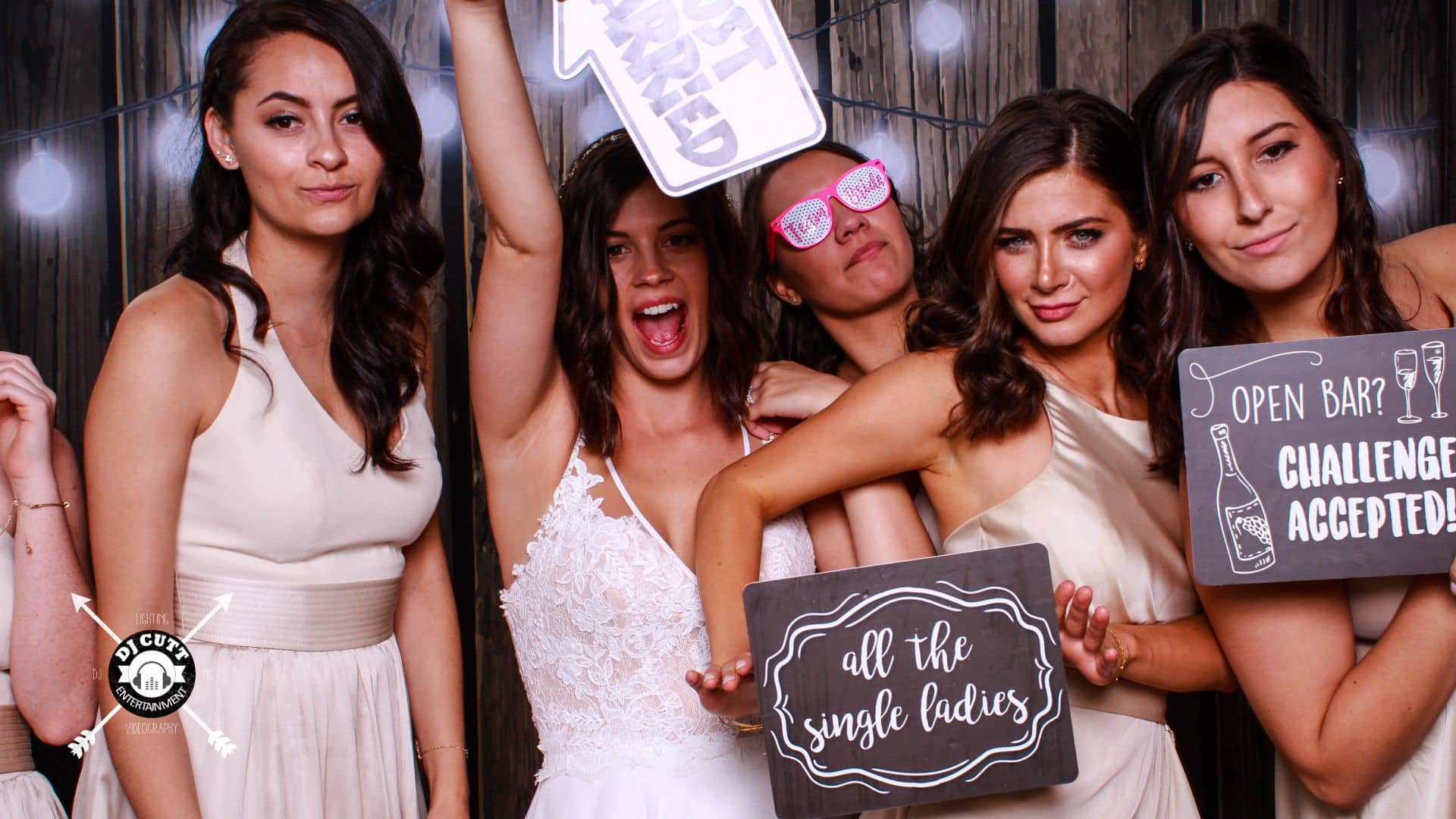 Wedding party women posing in photobooth with fun signs and props