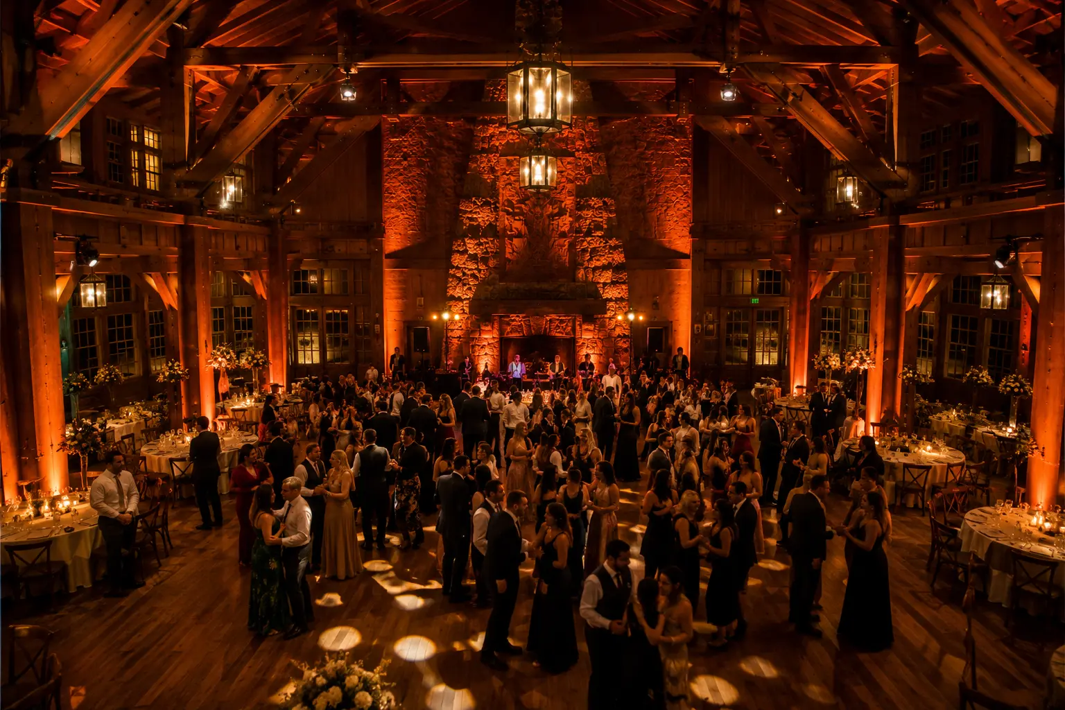 Timberline Lodge Oregon wedding reception interior with warm orange uplighting historic timber beams and dance floor energy at evening