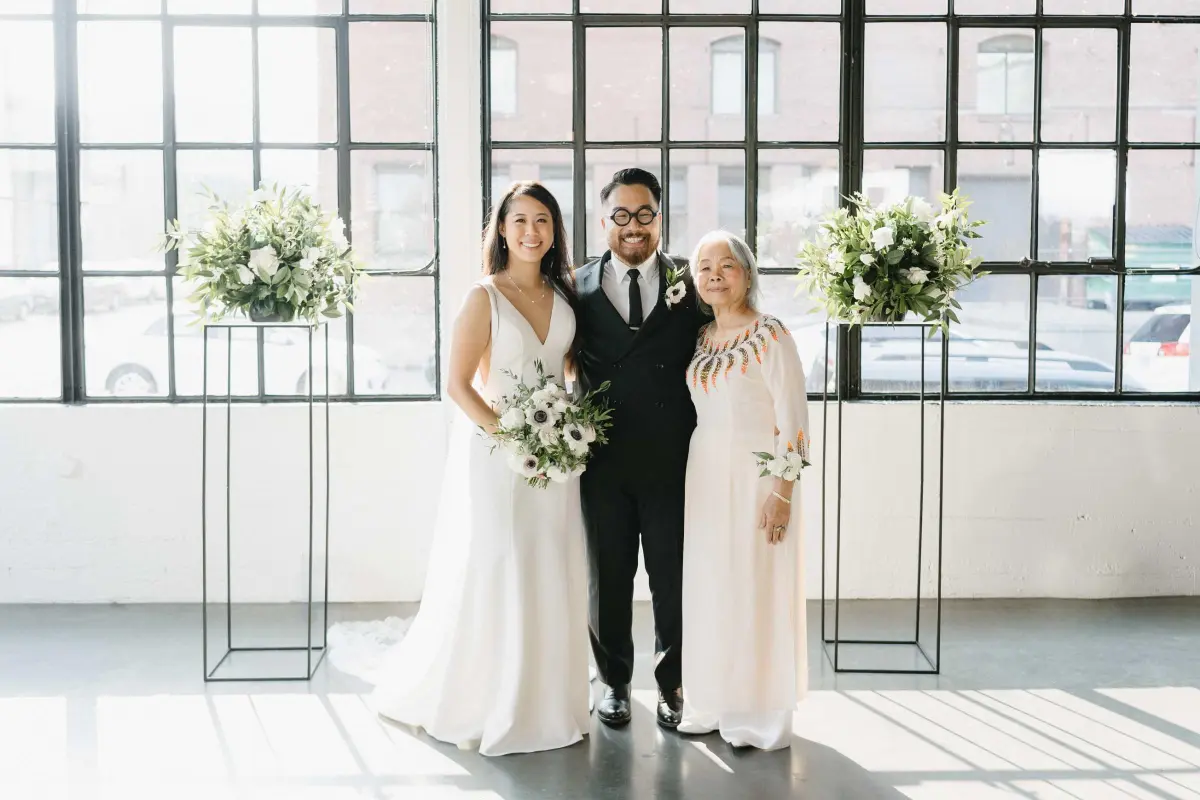 Tony and Rachel posing with a family member at their Castaway wedding in Portland, surrounded by natural light and elegant floral arrangements.