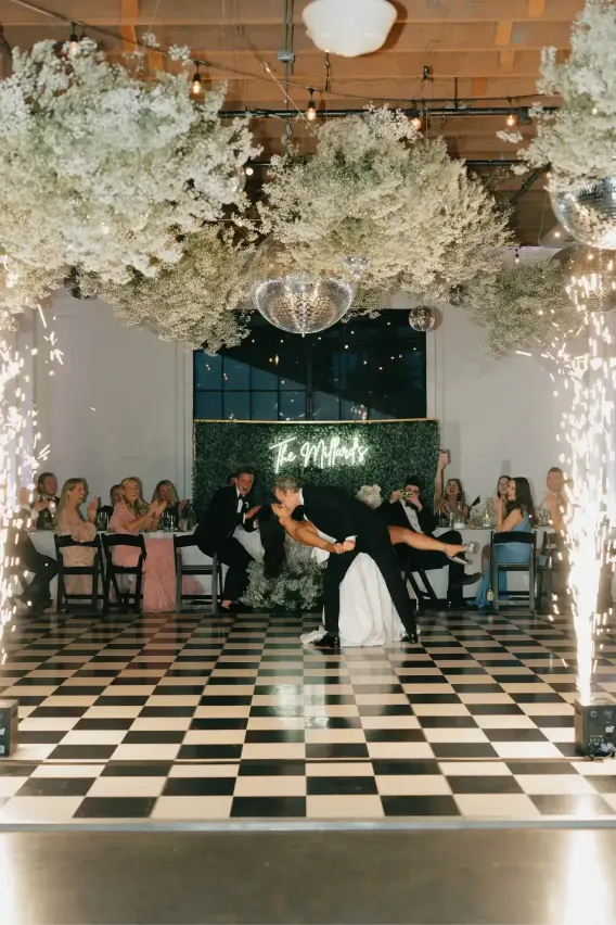 Bride and groom sharing a dramatic first dance at Castaway Portland Wedding Venue surrounded by indoor sparklers, disco balls, and suspended floral installations.