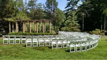 Beautiful outdoor wedding ceremony setup with white chairs and a rustic wooden arbor, highlighting the perfect venue to work with a professional wedding DJ who understands every stage of your wedding day.