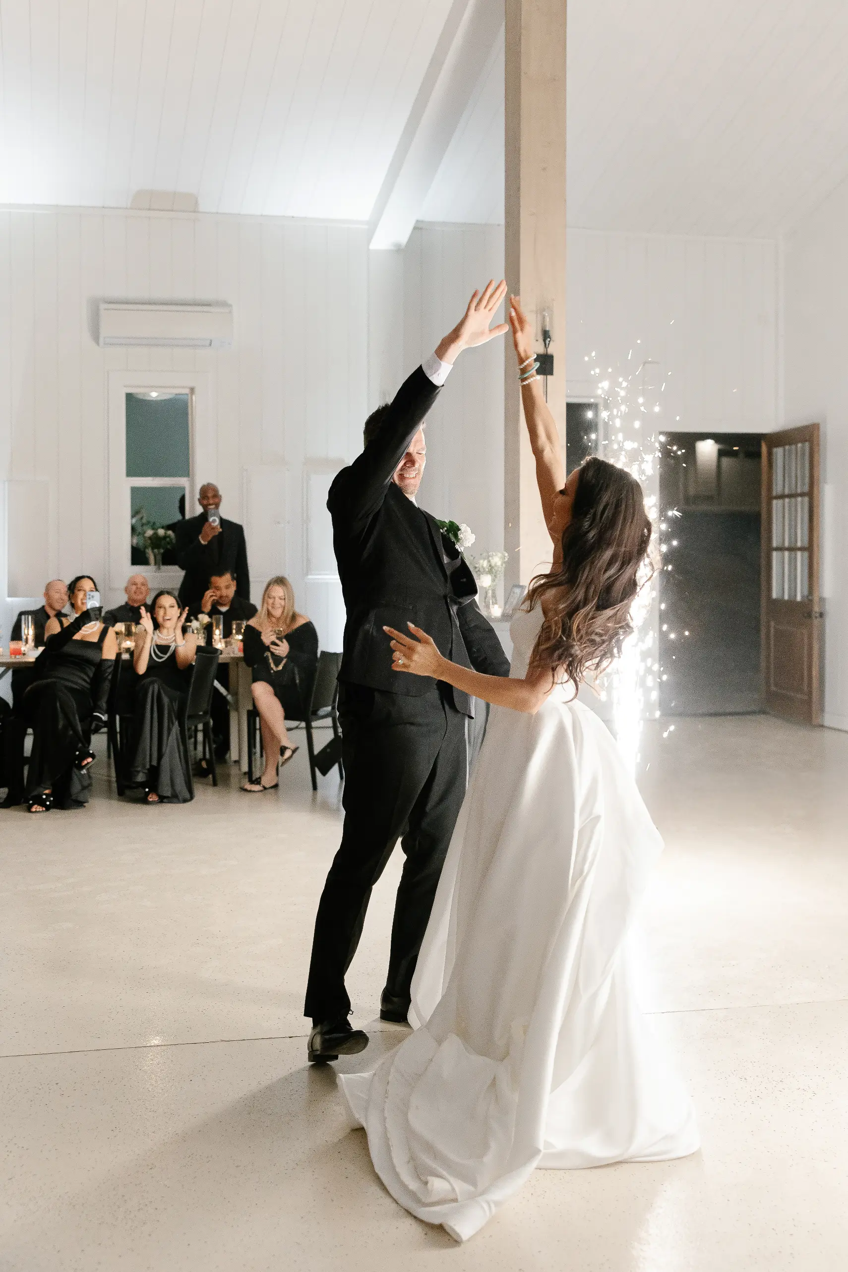 Lighting transforms Sage and Social wedding venue as the evening builds while the bride and groom share their first dance with indoor sparkler effects.