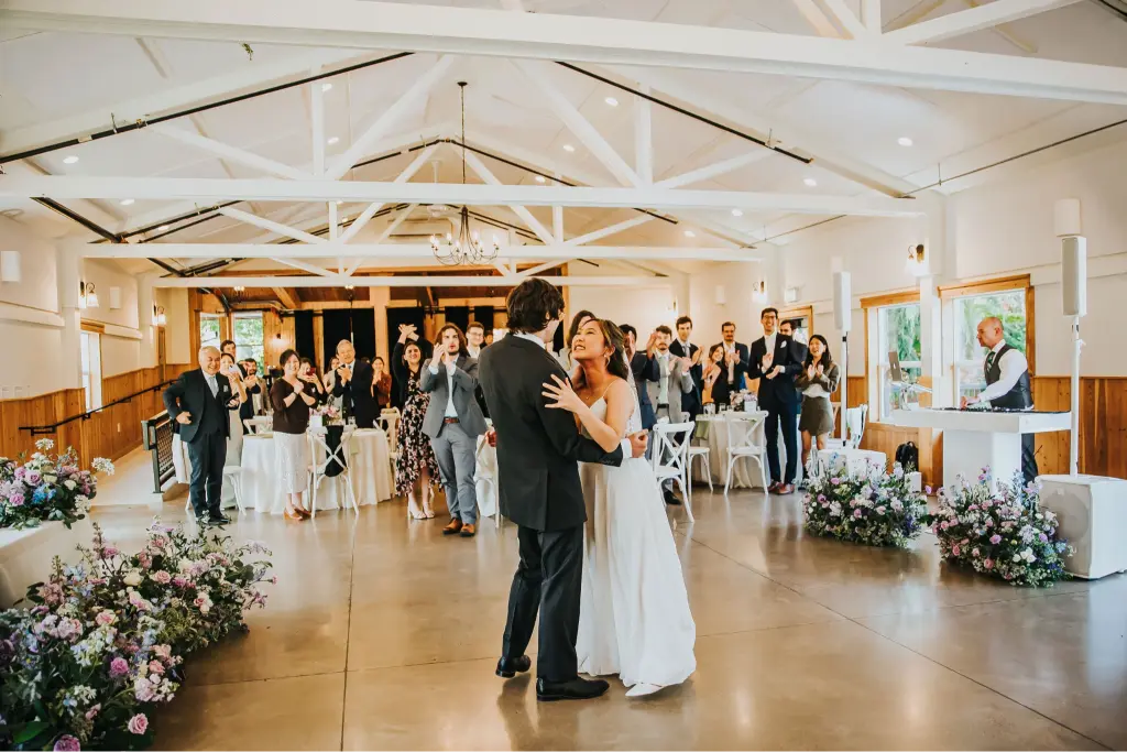 Bride and groom sharing their first dance at Aurora Vineyards inside The Barn at Countryside in Aurora Oregon, surrounded by cheering wedding guests.