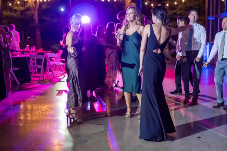 Wedding guests dancing under string lights during the outdoor reception at Water Oasis in Newberg, Oregon, with colorful DJ lighting creating a lively celebration.