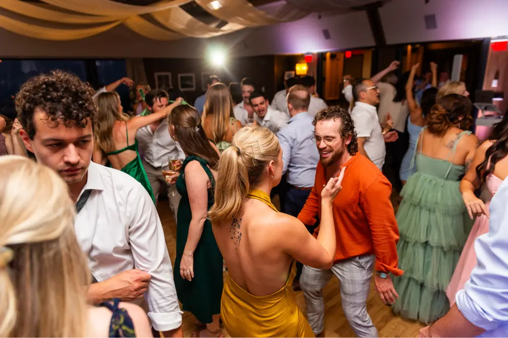 Wedding guests dancing and celebrating during a Timberline Lodge wedding reception with elegant lighting and a lively dance floor.