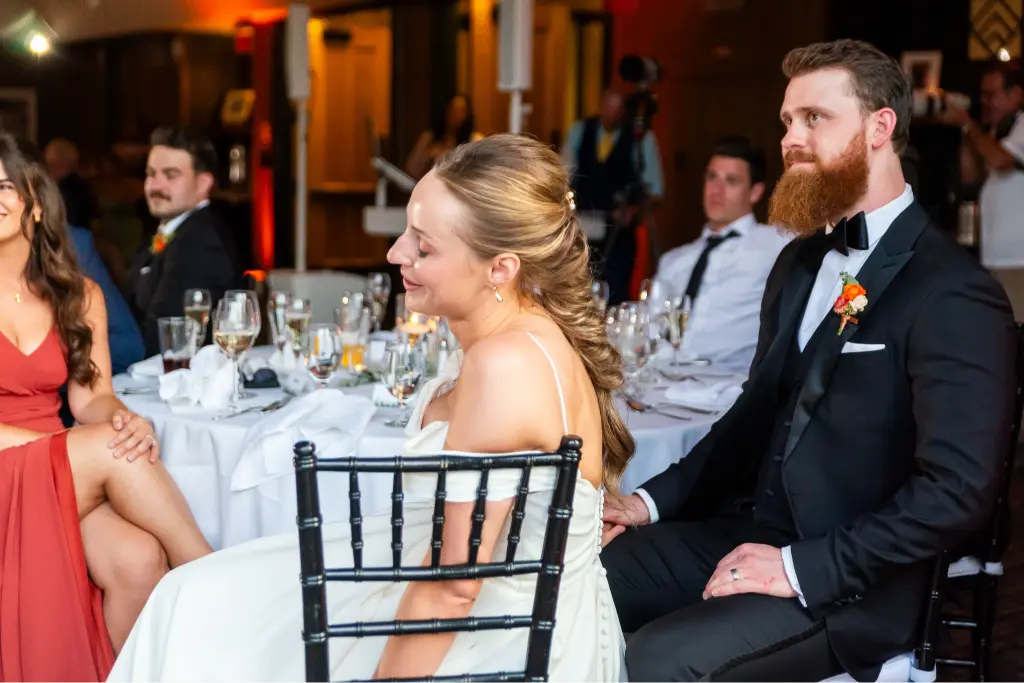 Bride and groom listening to heartfelt wedding speeches during their Timberline Lodge reception surrounded by family and friends.