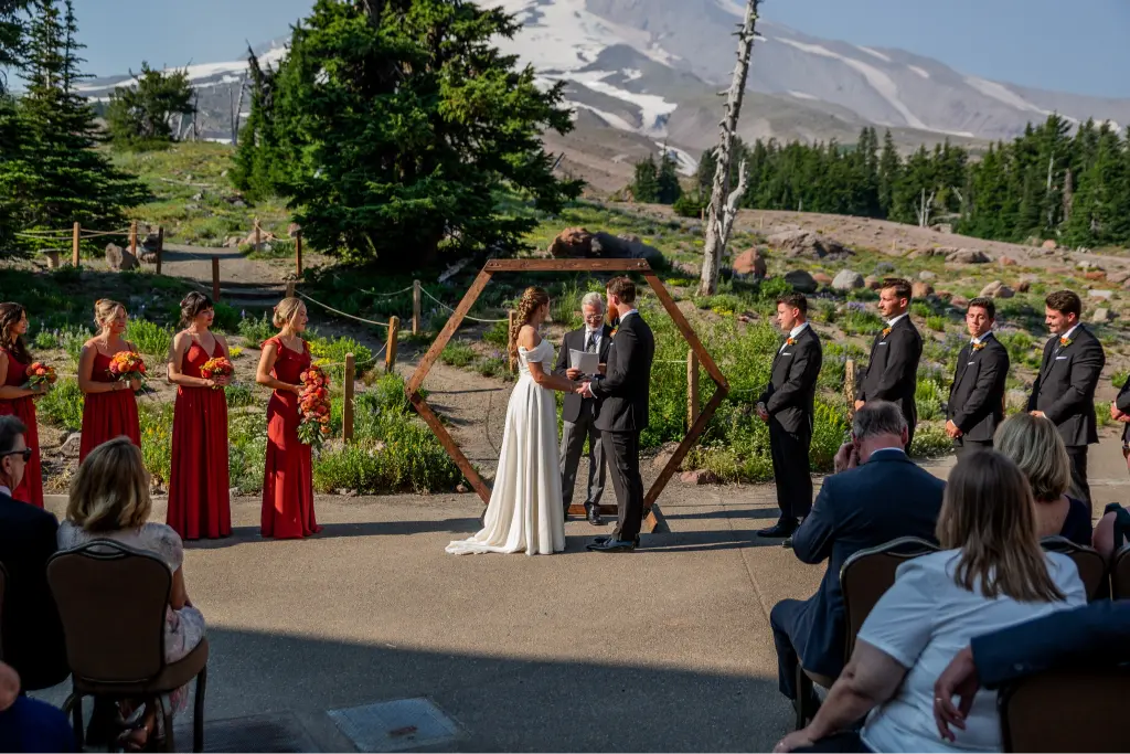 Bride and groom exchanging vows during an outdoor Timberline Lodge wedding ceremony with Mount Hood and alpine scenery in the background.