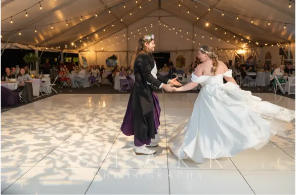 Newlyweds sharing their first dance under string lights at a Camp Cedar Ridge wedding reception.