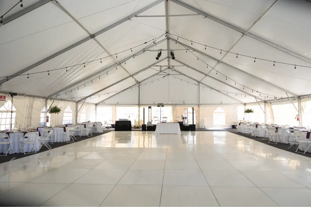 Elegant wedding reception tent setup at Camp Cedar Ridge with a spacious dance floor, café string lights, and DJ booth in Oregon.