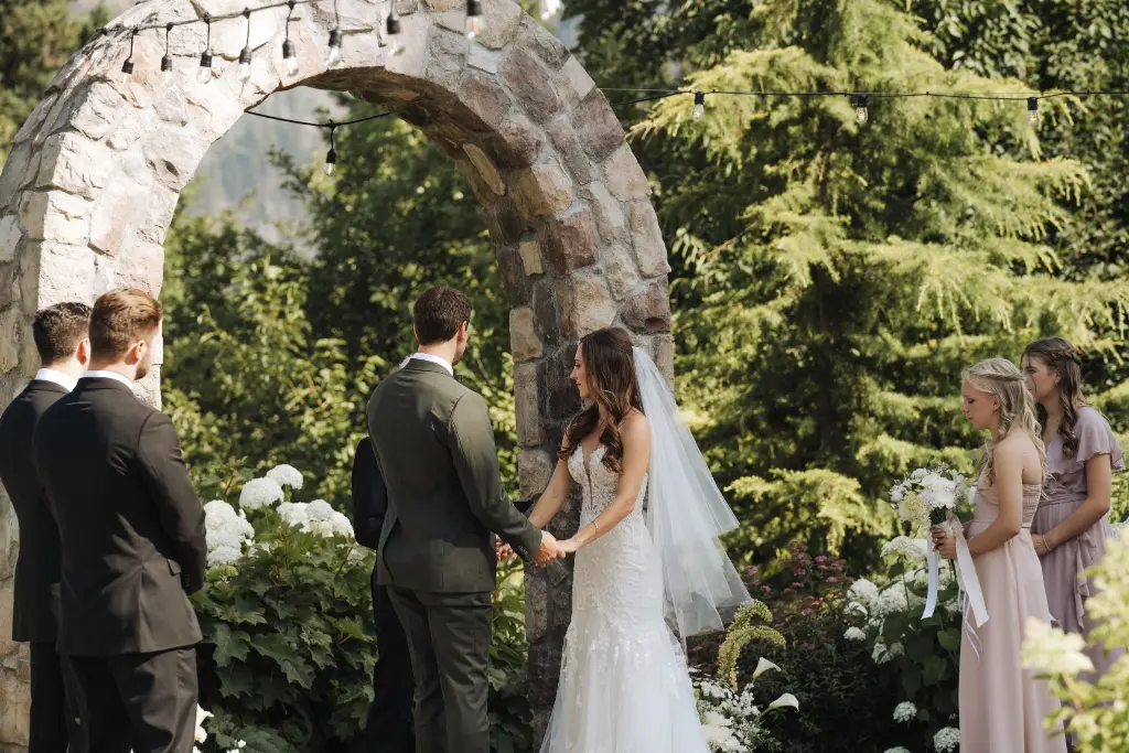 Bride and groom exchanging vows beneath the stone arch during a Cape Horn Estate wedding ceremony in Washington.