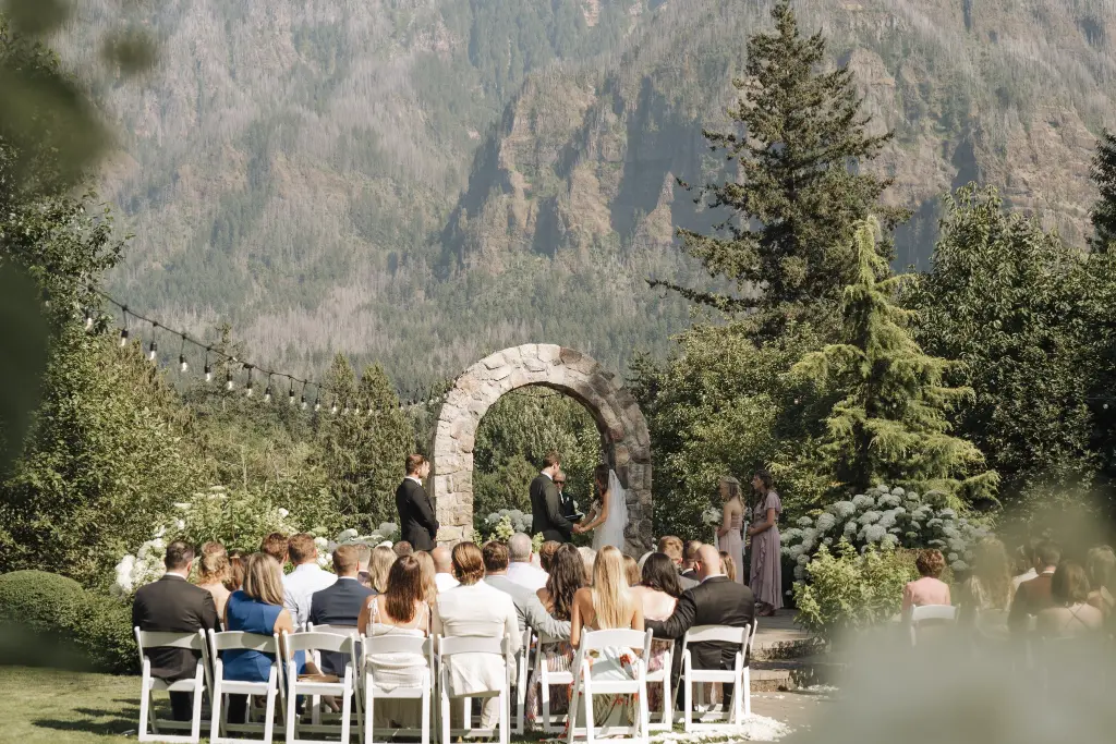 Outdoor wedding ceremony at Cape Horn Estate with a stone arch and breathtaking Columbia River Gorge mountain views.