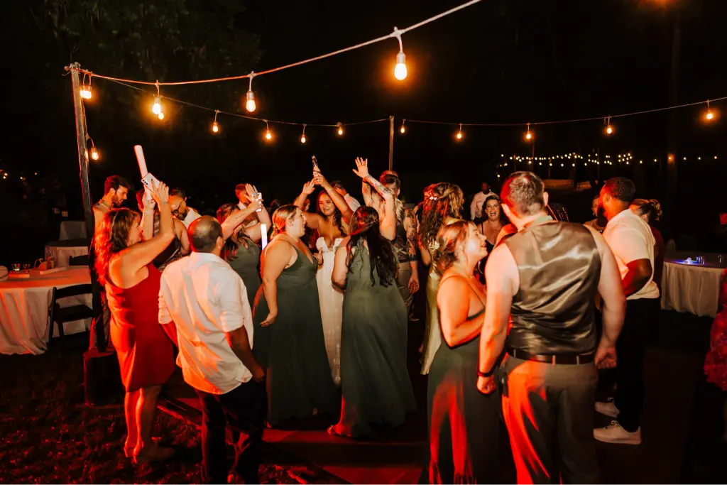 Wedding guests dancing under string lights during a lively outdoor reception at CedarVale Events, celebrating with the bride and groom on the dance floor.