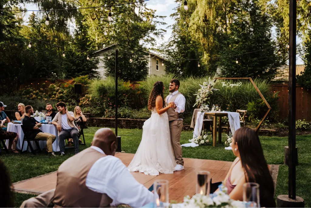 Bride and groom sharing their first dance on an outdoor dance floor during a romantic wedding reception at CedarVale Events surrounded by family and friends.