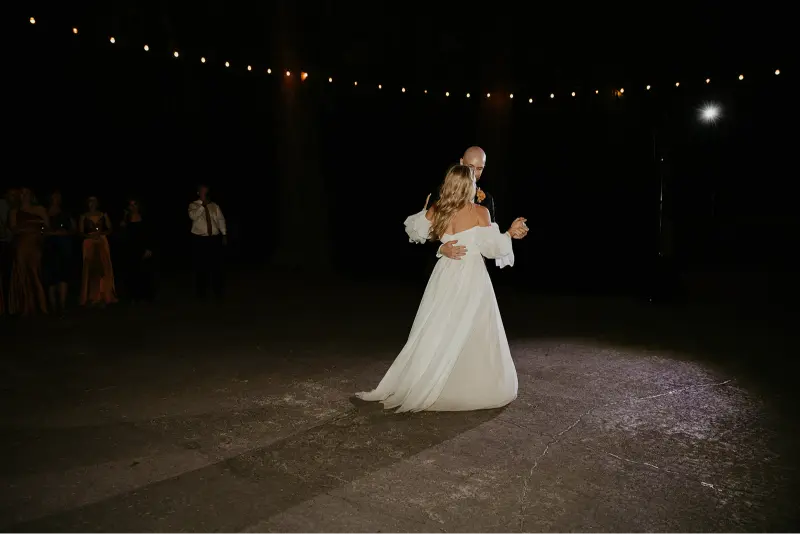 Bride and groom sharing their first dance under glowing string lights during an evening Wedding at Cedarville Lodge.