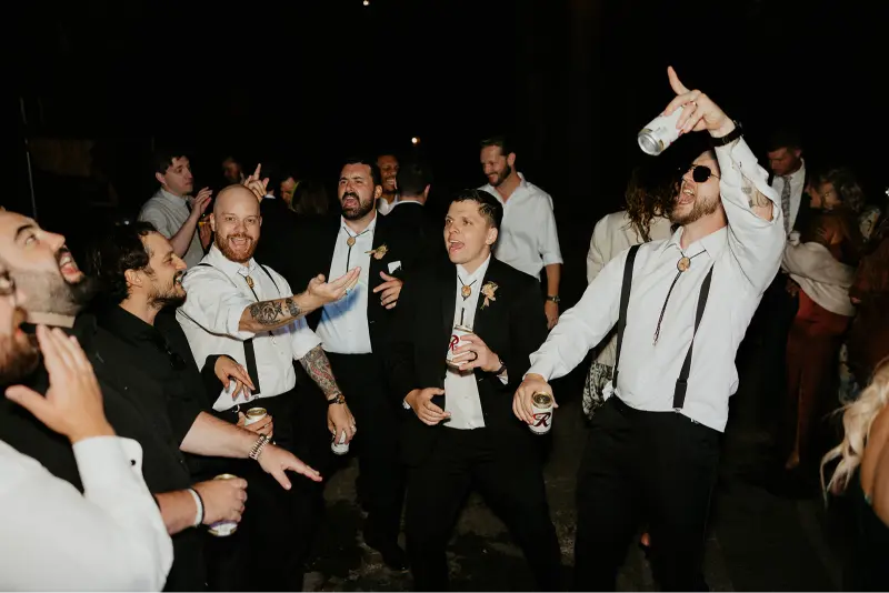 Groomsmen celebrating on the dance floor during a fun-filled Wedding at Cedarville Lodge reception with music, drinks, and lively energy.