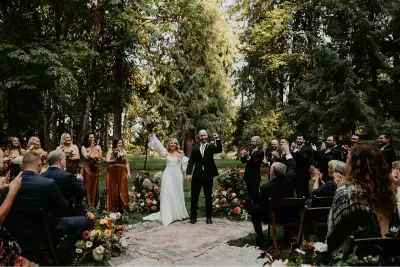 Bride and groom celebrating after saying "I do" during a beautiful outdoor Wedding at Cedarville Lodge surrounded by family, friends, and lush forest scenery.
