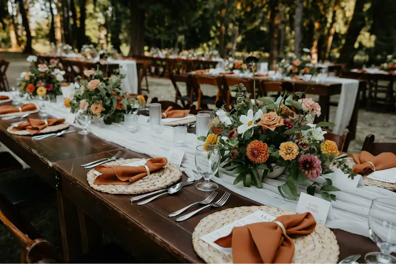 Elegant reception tables with lush floral centerpieces and rustic place settings during a Wedding at Cedarville Lodge surrounded by beautiful forest scenery.