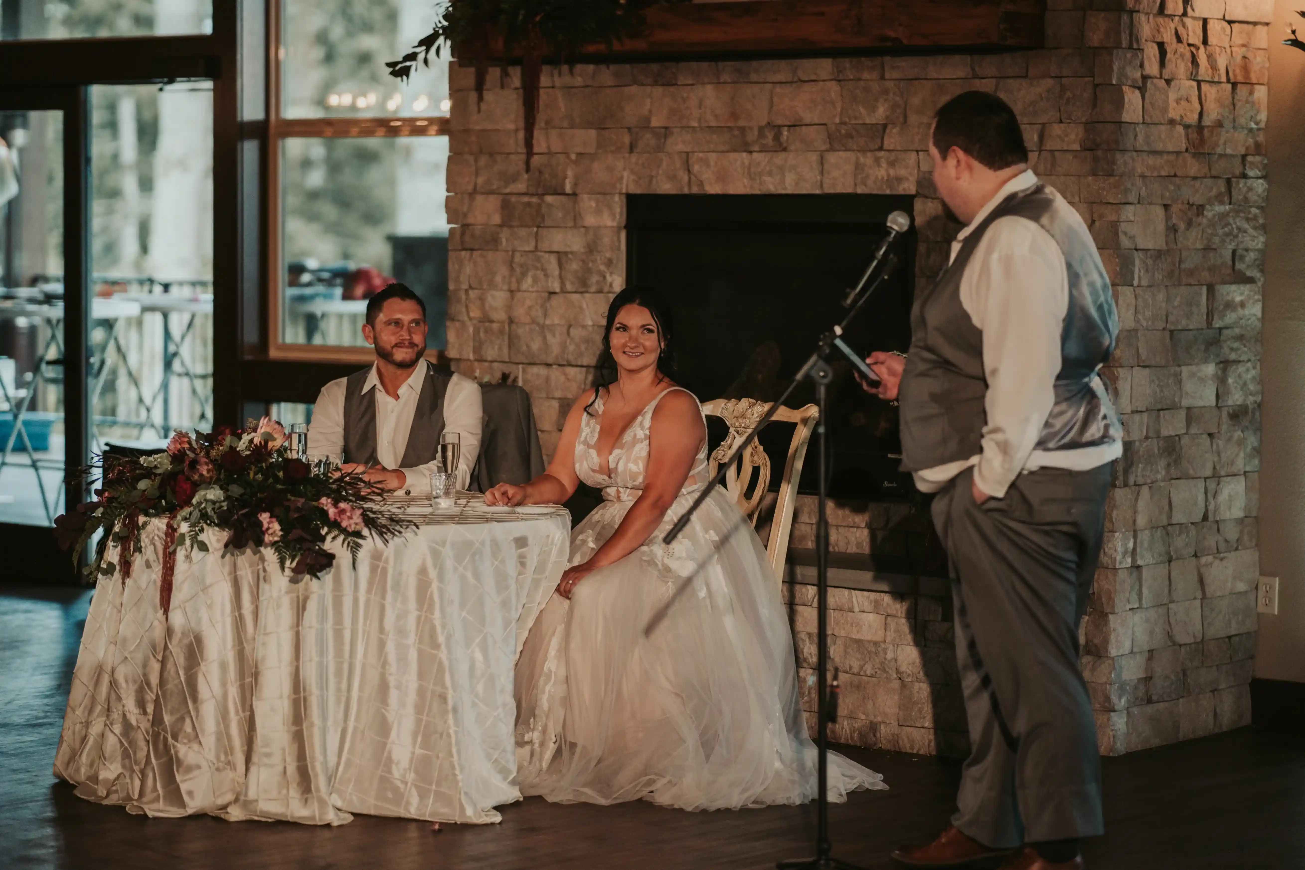 Wedding-reception-toast-at-the-Ecotrust-Building-in-Portland-with-the-bride-and-groom-listening-to-a-heartfelt-speech-by-the-fireplace.