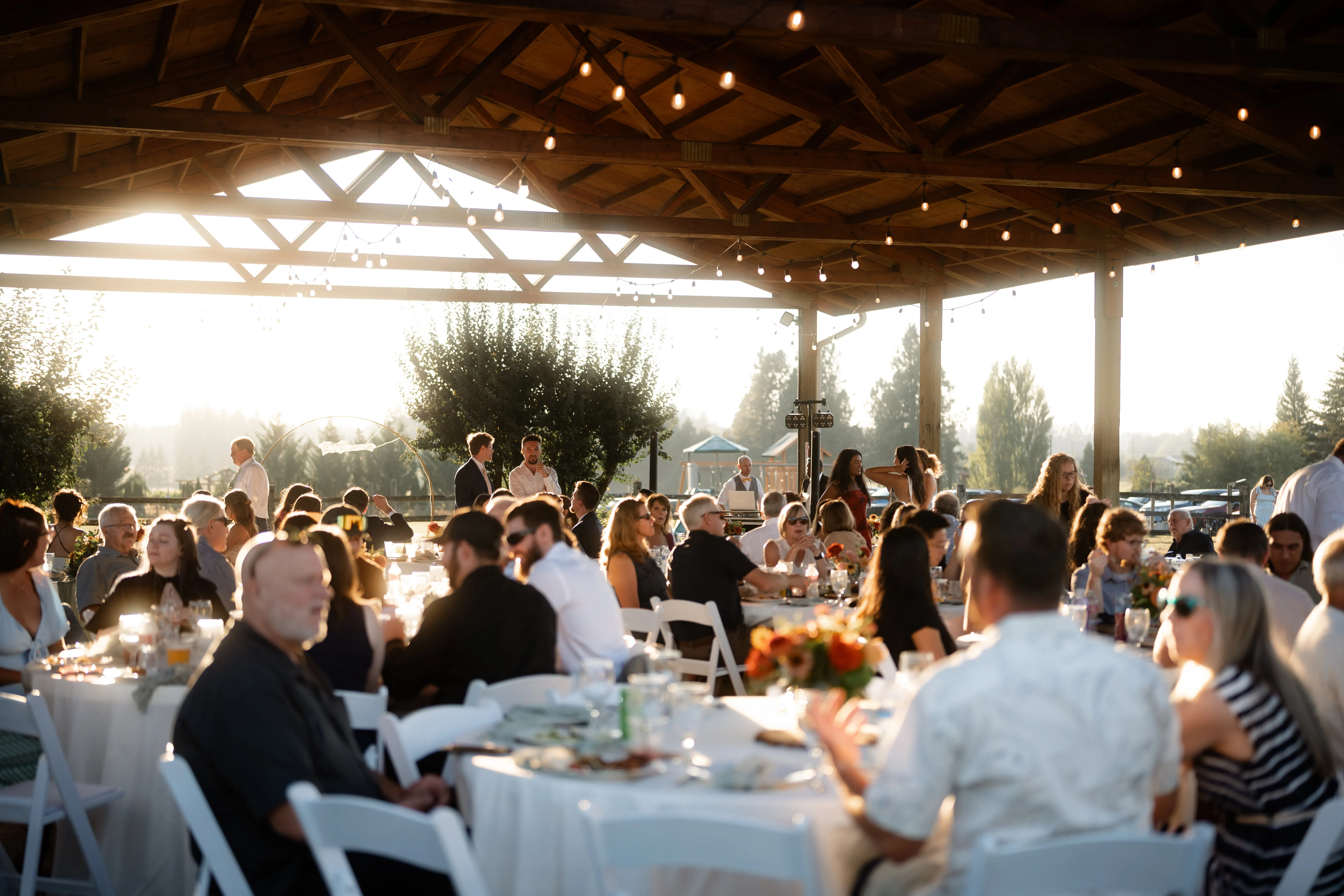 Outdoor-wedding-reception-at-Jacquot-Vineyard-with-guests-dining-under-a-rustic-pavilion-and-string-lights-in-Oregon