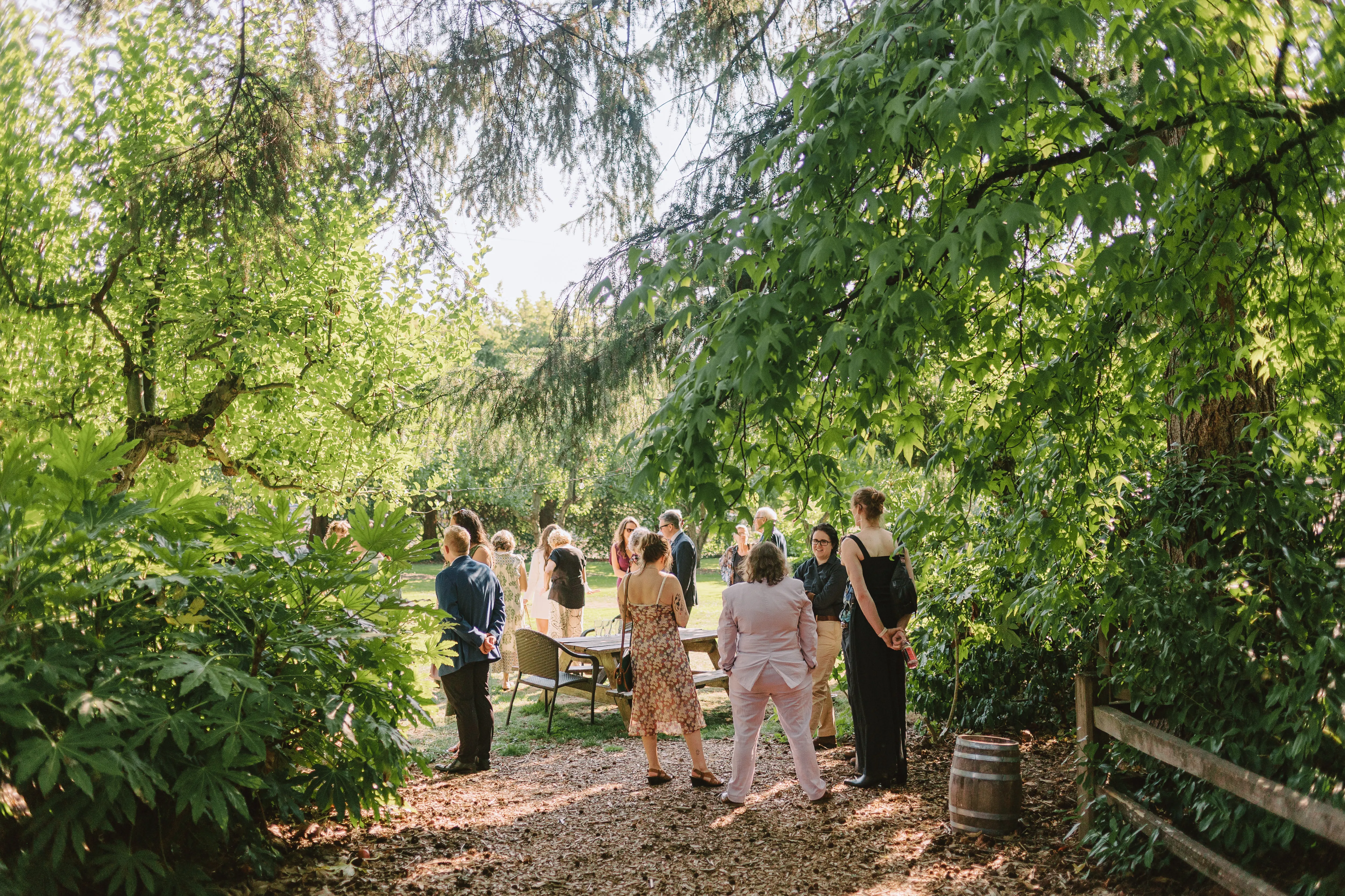 Guests-socializing-in-the-garden-during-a-Cornelius-Pass-Roadhouse-wedding-surrounded-by-mature-trees-and-lush-greenery-in-Hillsboro-Oregon.
