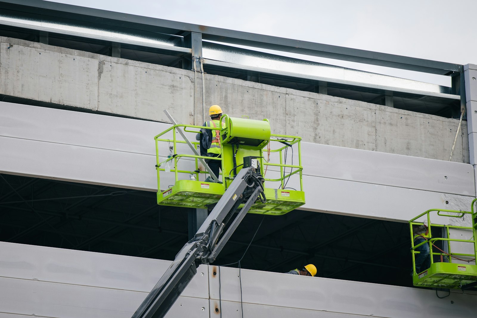 Crew member in hi-vis gear working from a boom lift on the facade of a commercial building