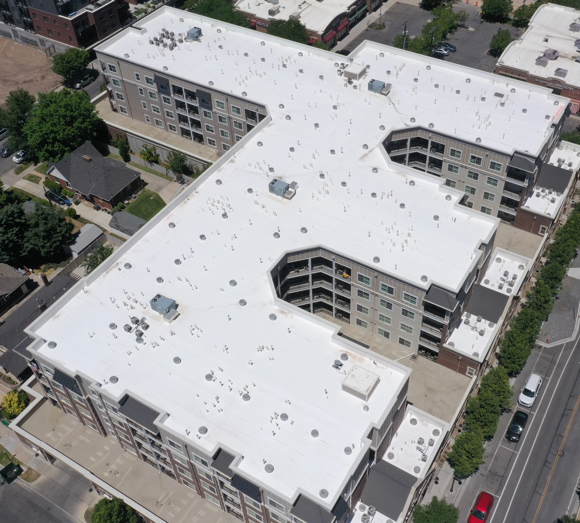 Aerial view of a completed white membrane roof on a multifamily building