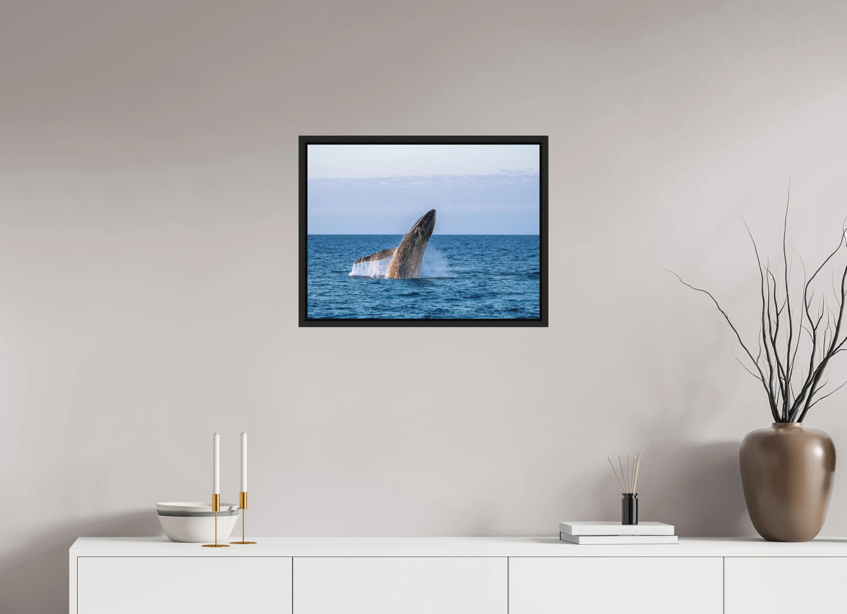 Fine art print “Unleashed” featuring a humpback whale breaching powerfully from the ocean surface, displayed in a floater frame in a modern living room setting.