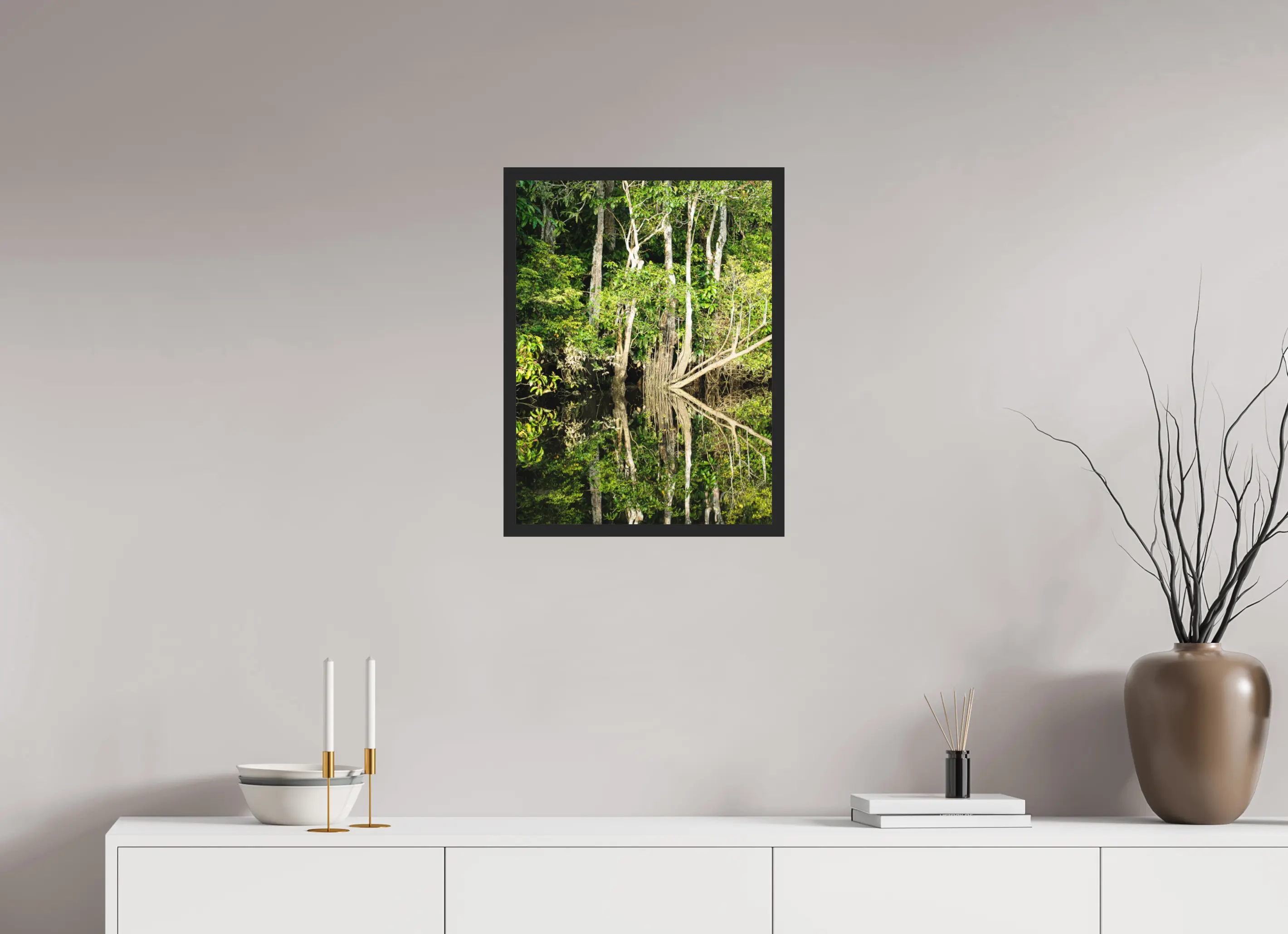 Fine art print “The Jungle Mirror” featuring dense Bornean rainforest trees perfectly reflected in still dark river water, displayed classic framed in a modern living room setting.